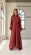 Front full view of woman wearing rust red long sleeve belted flowy maxi dress with stand collar