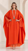 Front view of woman wearing orange cape sleeve kaftan maxi dress with lace trim