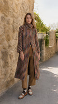 Full front view of model wearing rust multi high neck tweed long coat with brown trousers and loafers