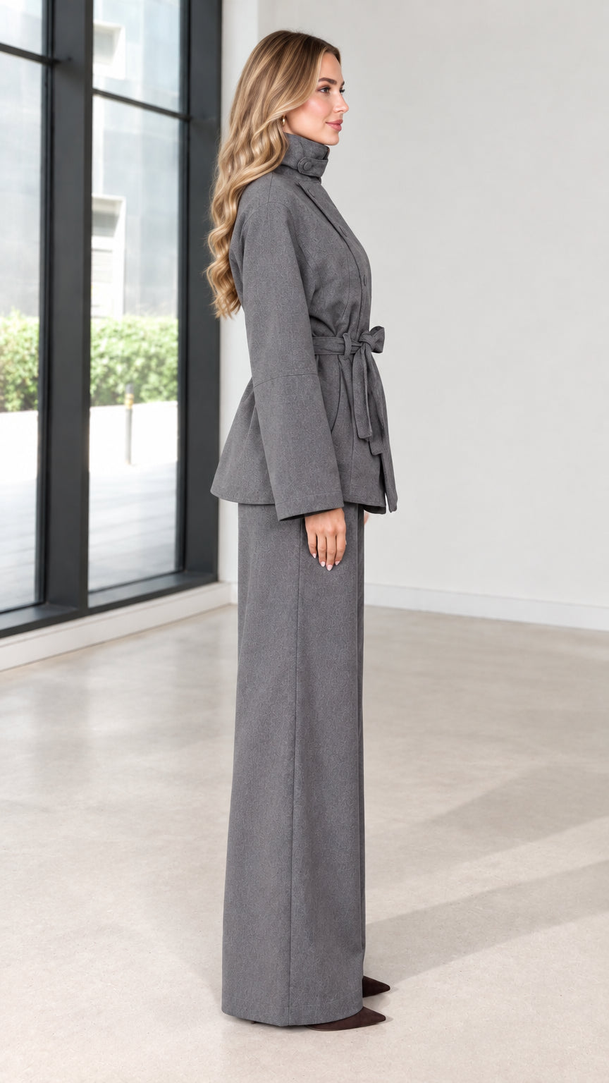 Side profile view of grey two-piece belted jacket and trouser set
