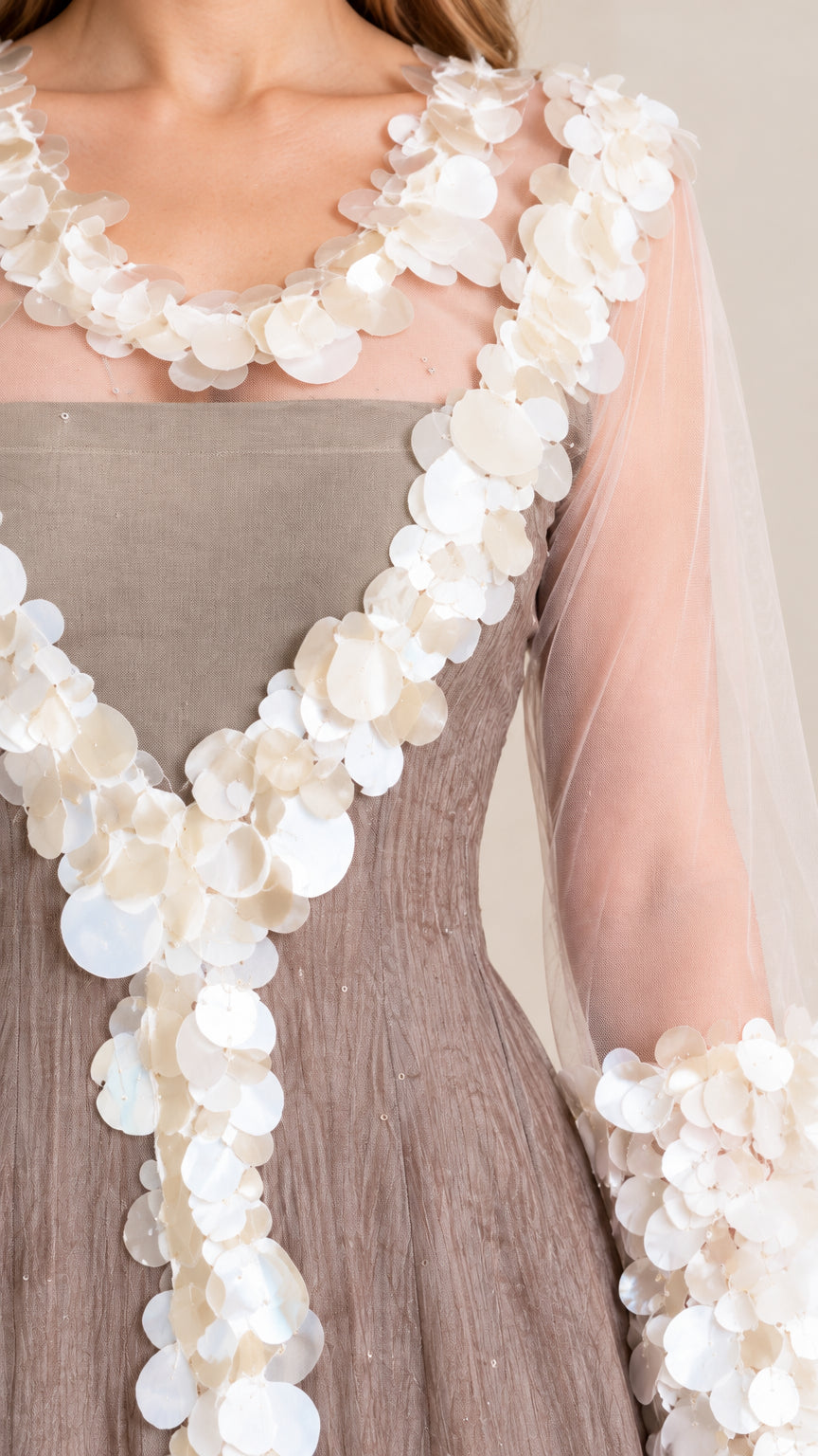 Close-up detail of sheer neckline, bodice, and sleeves adorned with dimensional circular petal paillettes